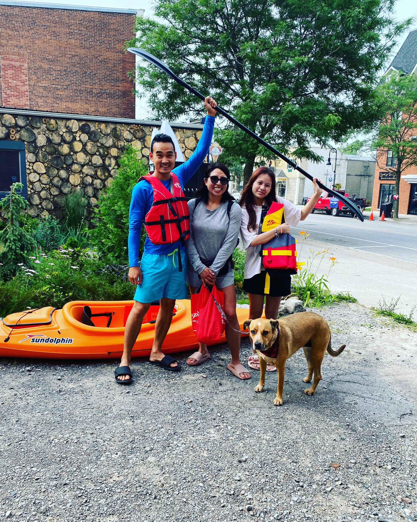 A family with their dog standing next to a kayak