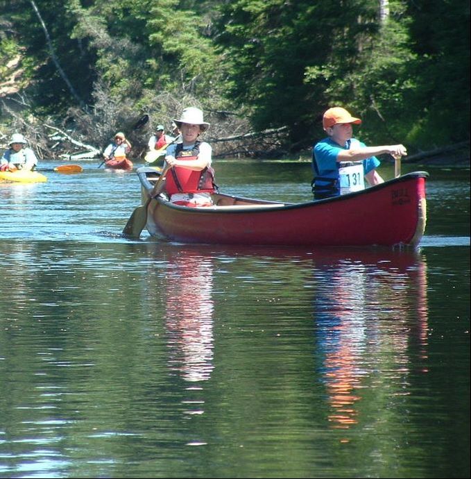 Two people paddling in a canoe on a lake with other people in canoes in the background