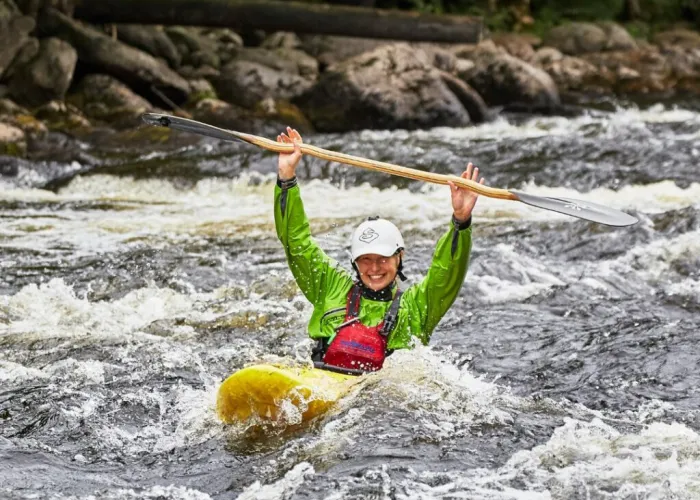 Person Kayaking Down Rapids