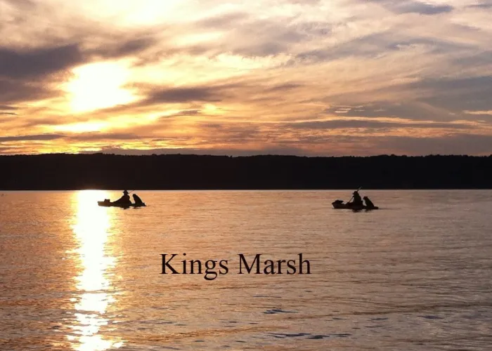 View of a lake with two boats with a sunset in the background