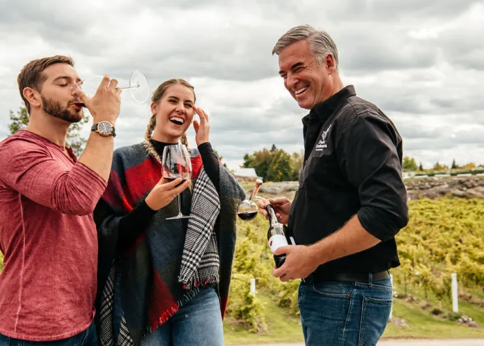 Three people enjoying wine in a vineyard