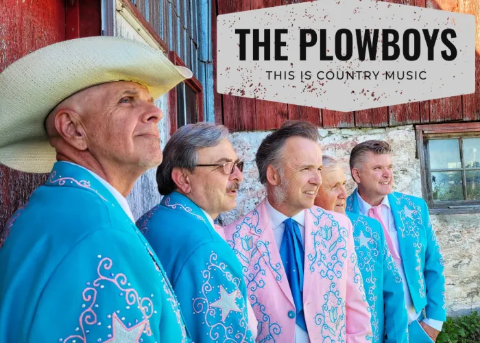 The Plowboys at Tweed and Co. Five men standing in blue and pink suits, with barn in background.