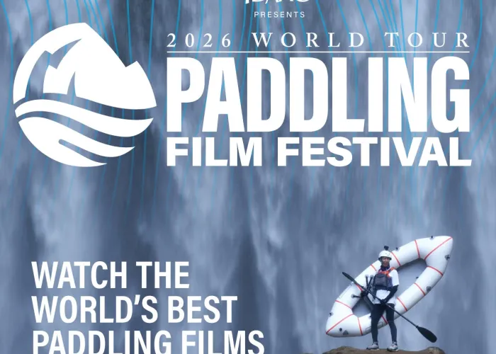 Event name, paddler in safety gear standing on cliff in front of waterfall