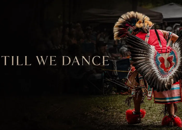 Black background, photo of person facing away from camera participating in pow wow on right, black on left with title of documentary in foreground